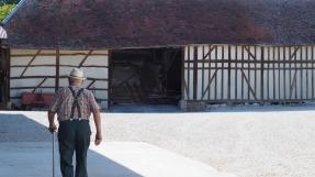 dos à la caméra, une paysan se dirige vers son étable